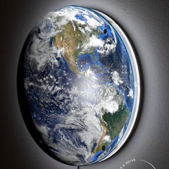 Side view of the Planet Earth wall light glowing on a dark wall
