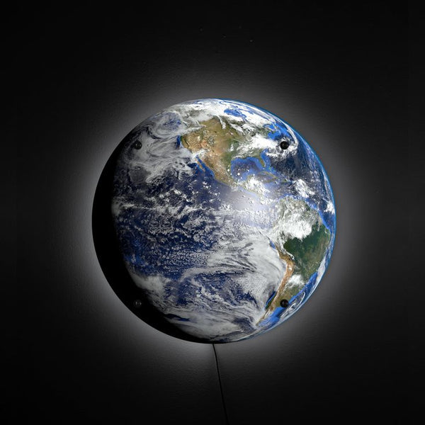 Planet Earth LED wall lamp with a soft halo glow on a dark wall
