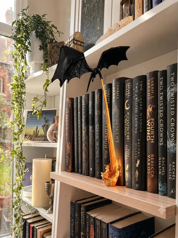 Dragon lamp on a bookshelf, flame base resting beside a row of books